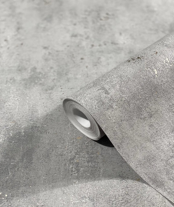Marburg City Glam 32614 A gray textured wallpaper roll resting on a matching unrolled sheet, showing a concrete-like mottled surface.