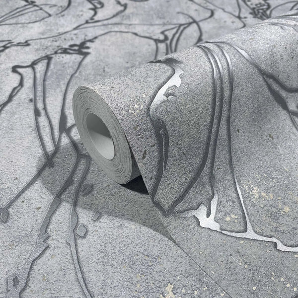 Marburg City Glow 34254 Close-up of a gray wallpaper roll with large abstract curving line pattern and speckled texture, partially unrolled on the same wallpaper.