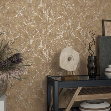 Marburg City Glow 34255 Textured brown wallpaper with flowing abstract leaf-like outlines behind a console vignette with a sculptural disc, dark glass vase, ceramic bowls, framed artwork, and a glass vase of dried grasses.