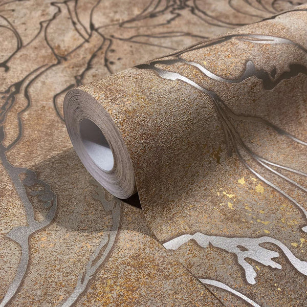 Marburg City Glow 34255 Close-up of a wallpaper roll resting on matching paper, showing a mottled brown ground with flowing metallic lines and small gold speckles.