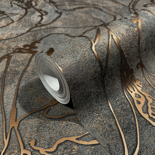 Marburg City Glow 34256 Close-up of a wallpaper roll on matching surface, showing a dark charcoal background with metallic copper abstract lines and a textured finish.
