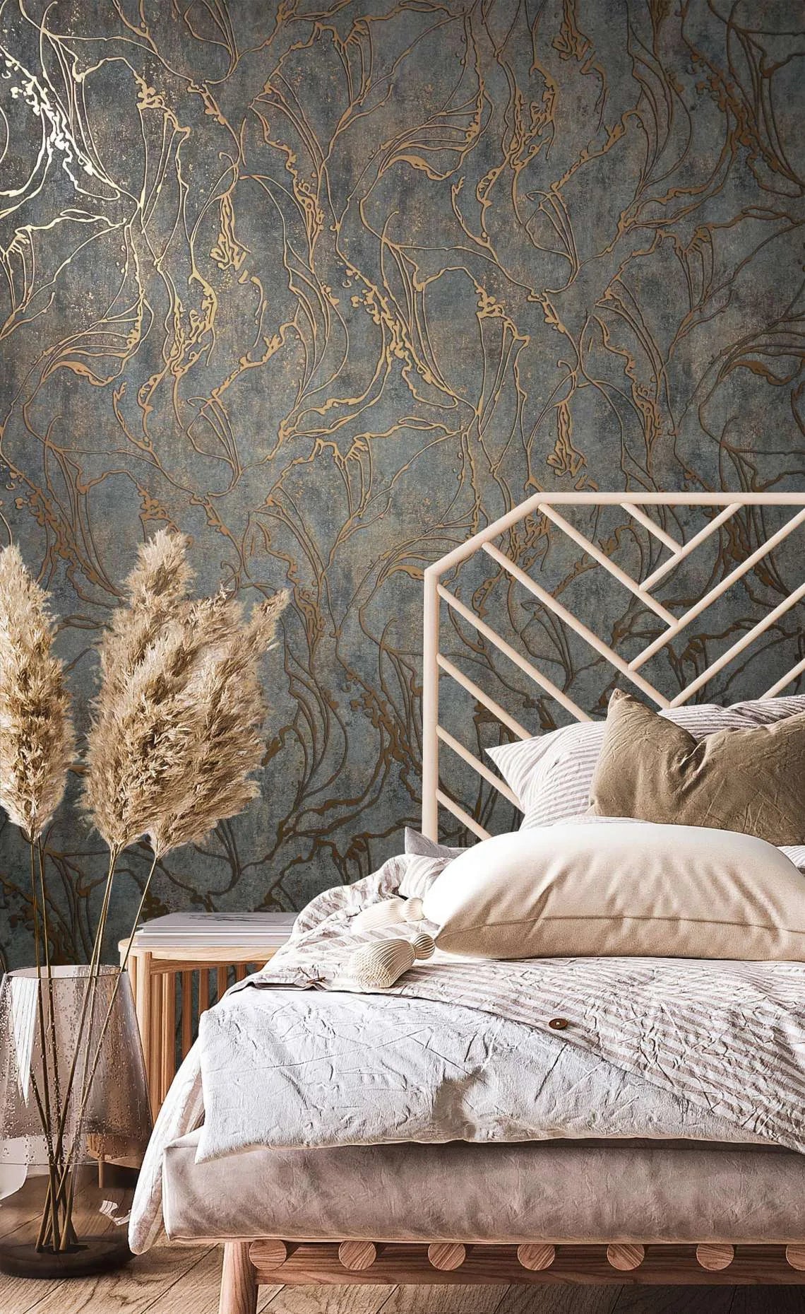 Marburg City Glow 34256 Bedroom scene showing a dark textured wallpaper with metallic abstract linework behind a bed with a geometric headboard and pampas grass in a glass vase.
