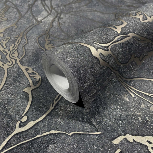 Marburg City Glow 34257 Close-up of a wallpaper roll on the same pattern, showing a dark charcoal background with metallic gold abstract flowing lines and a speckled texture.