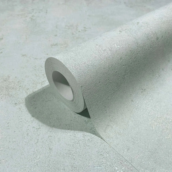 Marburg City Glow 34266 Close-up of a light gray textured wallpaper roll partially unrolled on a matching surface, showing the tonal mottled pattern.