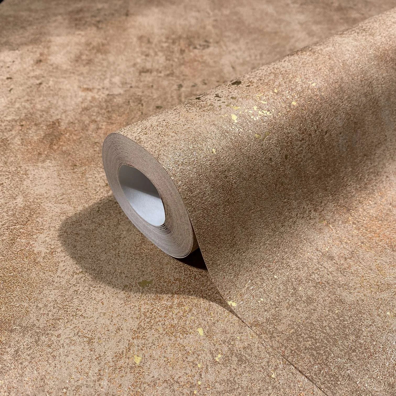 Marburg City Glow 34268 Close-up of a brown textured wallpaper roll with scattered metallic gold flecks resting on the same pattern.