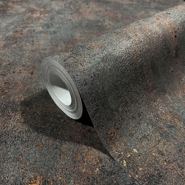 Marburg City Glow 34270 Angled close-up of a wallpaper roll on the same surface, showing a black ground with copper-brown mottled texture.