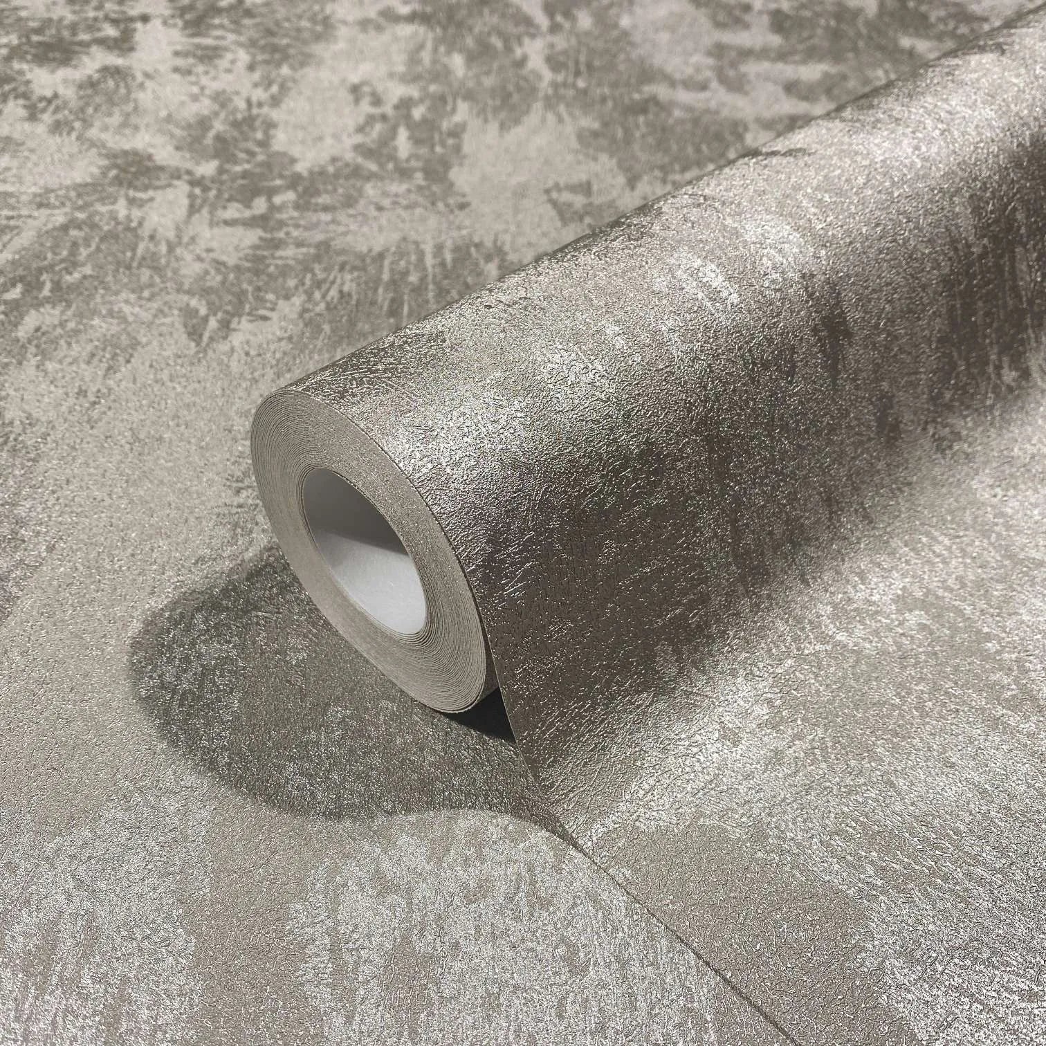 Marburg City Glow 34274 Close-up of a wallpaper roll resting on a matching unrolled sheet, showing a mottled gray pattern with a subtle pearlescent sheen.