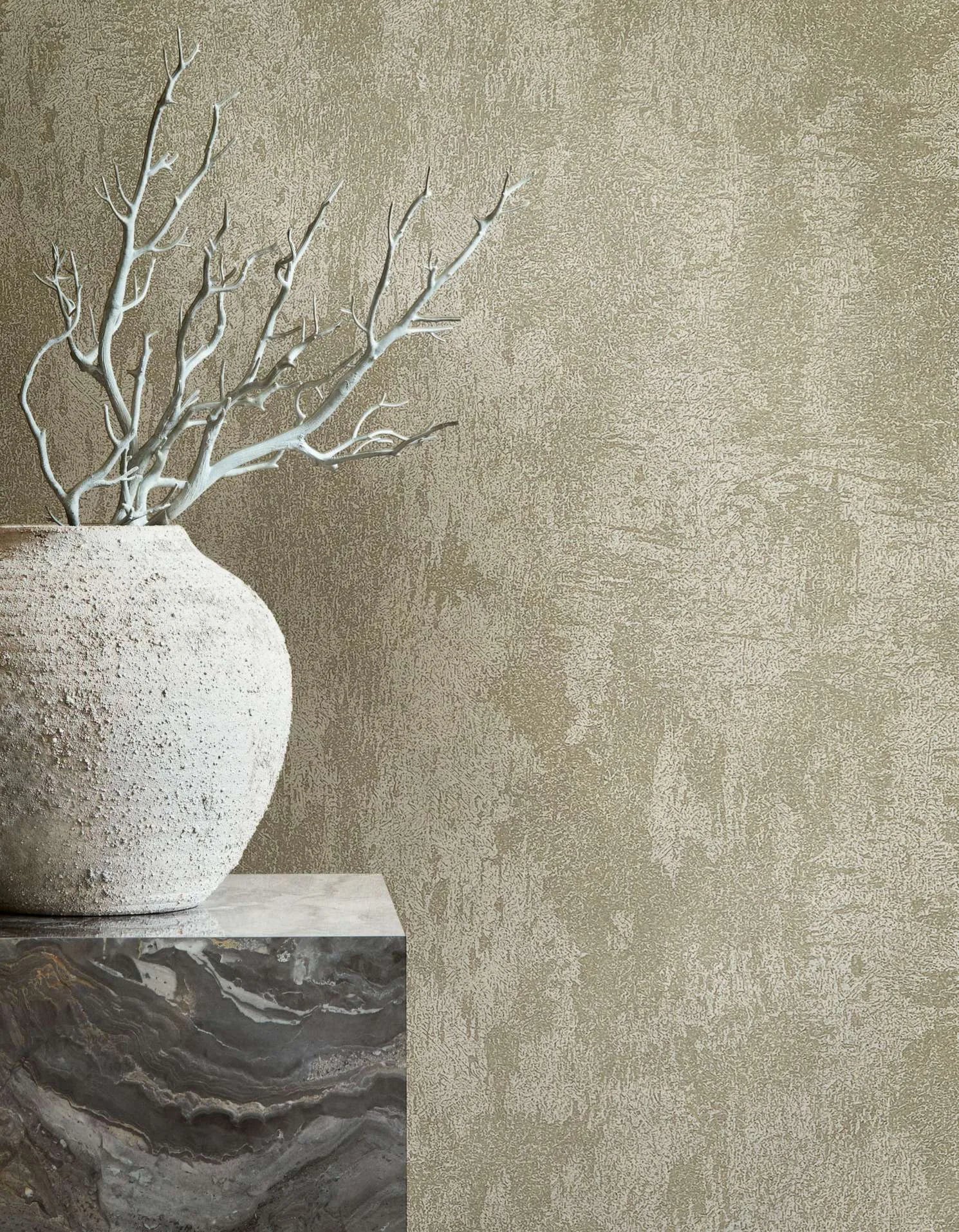 Marburg City Glow 34276 Tonal beige abstract textured wallpaper behind a rough stone vase with pale branches on a marble pedestal.