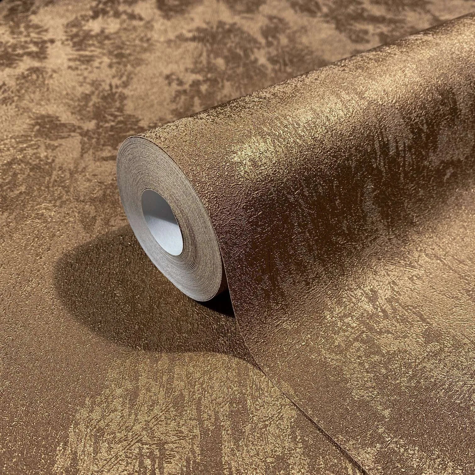 Marburg City Glow 34277 Close-up of a copper-toned textured wallpaper roll resting on matching unrolled wallpaper with a metallic sheen.