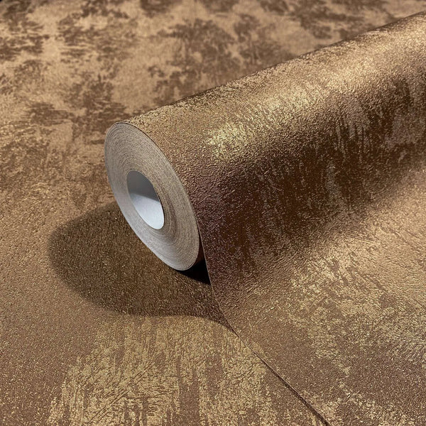 Marburg City Glow 34277 Close-up of a copper-toned textured wallpaper roll resting on matching unrolled wallpaper with a metallic sheen.