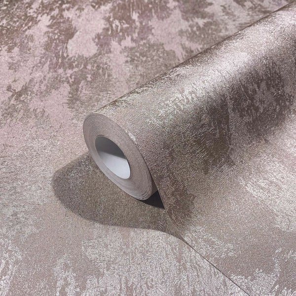 Marburg City Glow 34279 Wallpaper roll resting on a matching unrolled sheet, showing a soft pink mottled texture with a subtle metallic sheen.