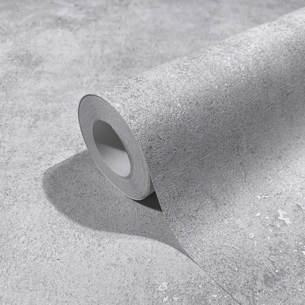 Marburg City Glow 34281 Close-up of a gray textured wallpaper roll partially unrolled on the same material, showing a concrete-like surface with fine speckling.