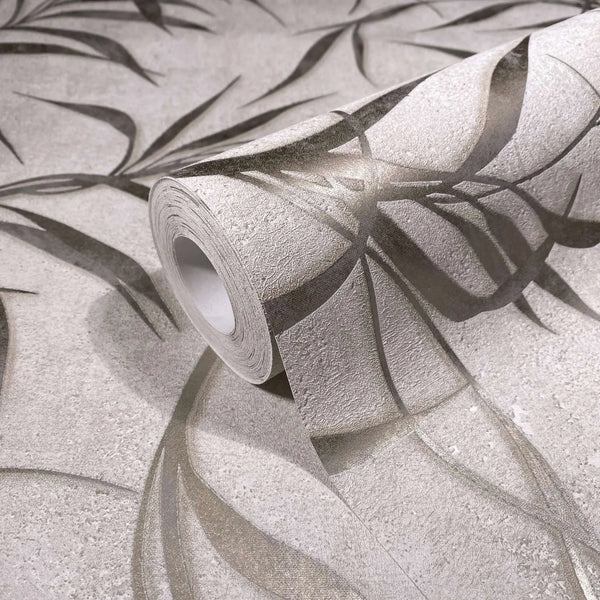 Marburg City Glow 34284 Angled product photo of a wallpaper roll on a matching sheet, showing a light neutral background with overlapping leaf silhouettes and a textured surface.
