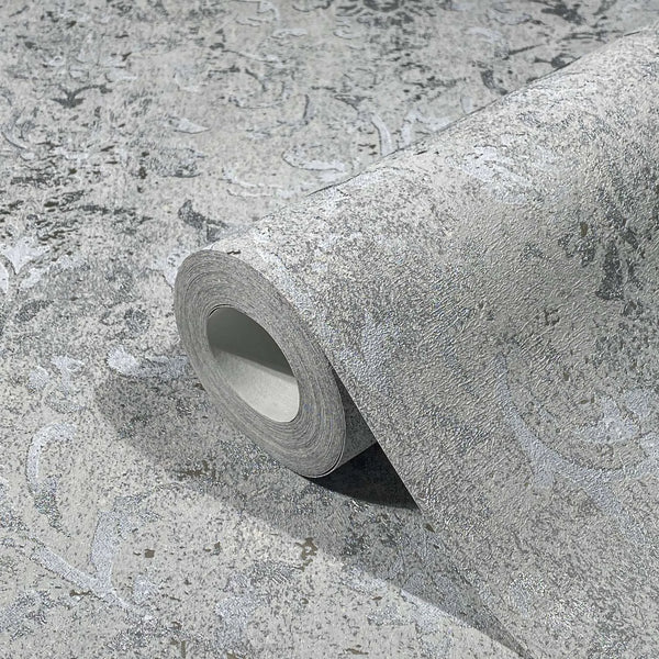 Marburg City Glow 34294 A gray textured wallpaper roll resting on the same pattern, showing a subtle scroll motif with a distressed look.
