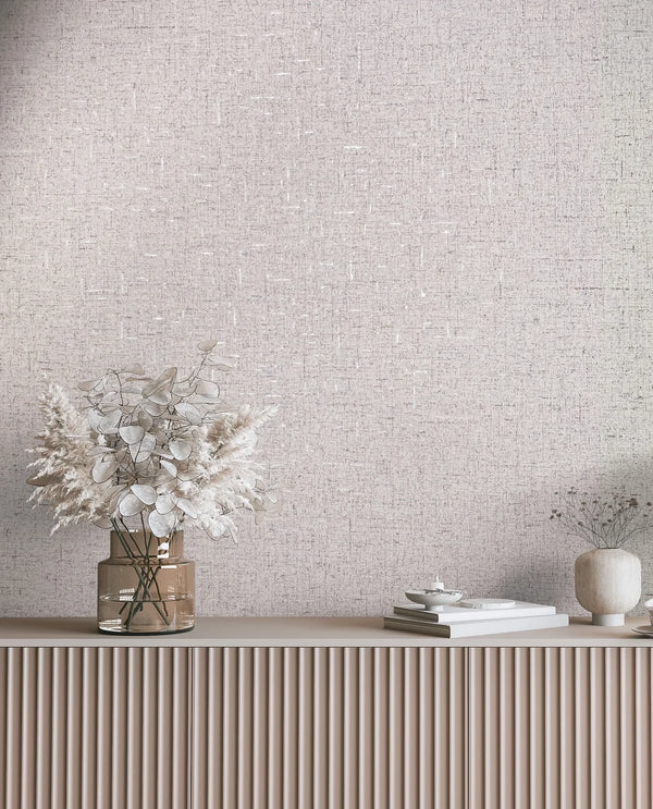 Marburg City Romance 35113 Light beige and gray crosshatch wallpaper behind a fluted console styled with a glass vase of dried leaves, a small ceramic vase with stems, stacked books, and a shallow dish.