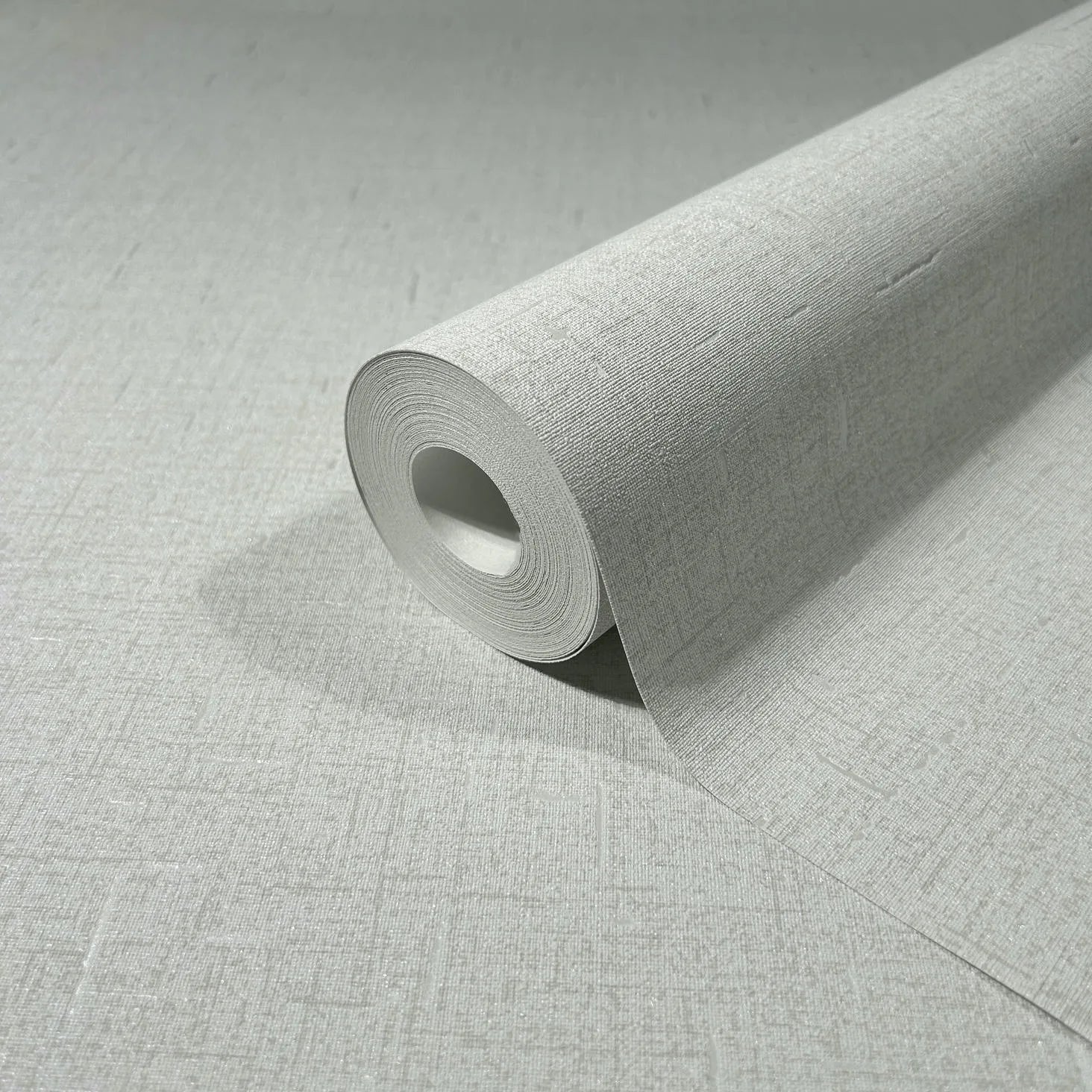 Marburg City Romance 35116 Close-up of a light gray textured wallpaper roll resting on the same pattern, showing a fine crosshatch surface.