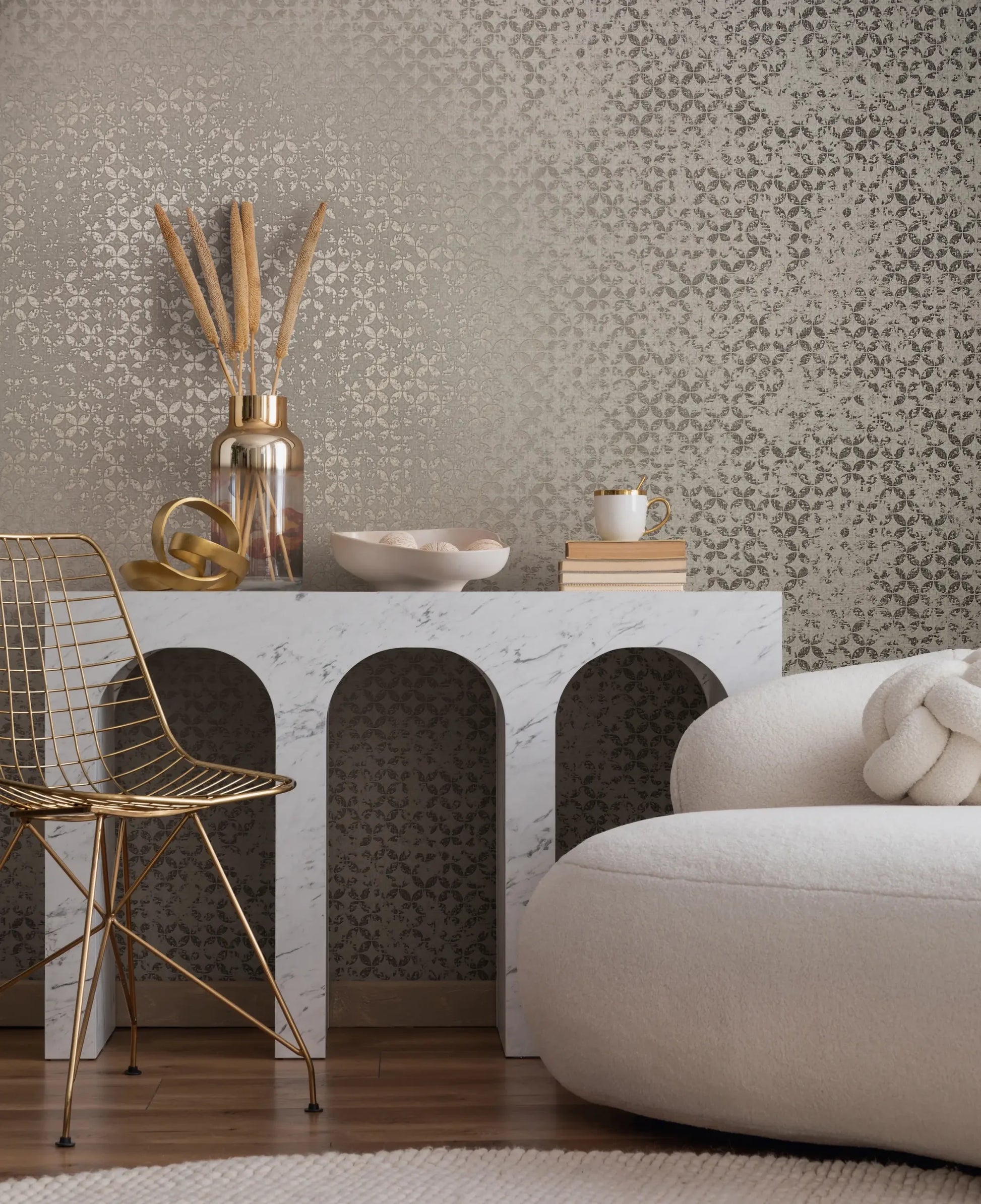 Marburg City Romance 35118 Tonal gray wallpaper with a small ornate pattern, shown behind a white marble-arch console with decor, a gold wire chair, and a rounded cream sofa.
