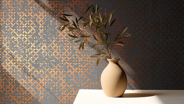 Marburg City Romance 35119 Dark wallpaper with a small repeating copper circular pattern on a charcoal ground; a ceramic vase with a leafy branch sits on a light tabletop with shadows.