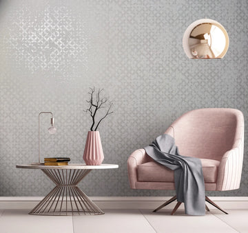 Marburg City Romance 35121 Tonal light gray damask wallpaper with a soft sheen shown in a styled room featuring a pink armchair with a draped throw, a round wire-base table with a small lamp, books, and a faceted vase with branches, plus a round pendant light.