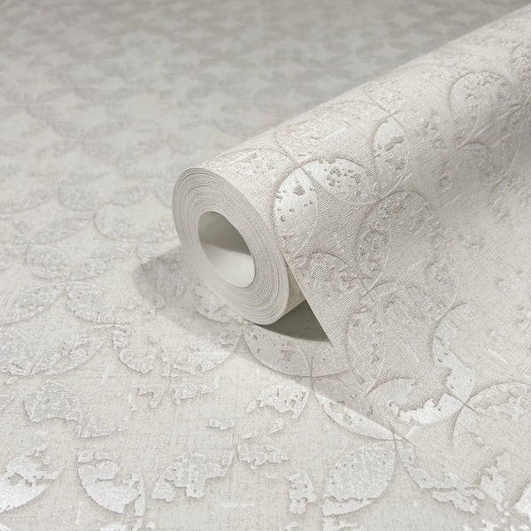 Marburg City Romance 35122 Close-up of a wallpaper roll resting on the same wallpaper, showing a tone-on-tone beige embossed petal pattern with a textured surface.