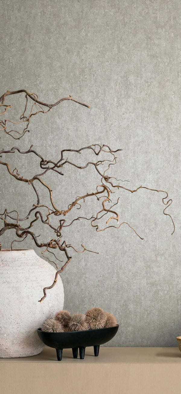 Marburg 35134 wallpaper lounge feature wall with a simple console, large ceramic vase of twisting branches and a black footed bowl of dried pods, calm and natural.