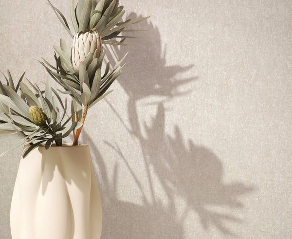 Marburg 35139 wallpaper lounge feature wall with subtle textured finish, sculptural vase of protea stems casting soft shadows for a serene minimalist look.