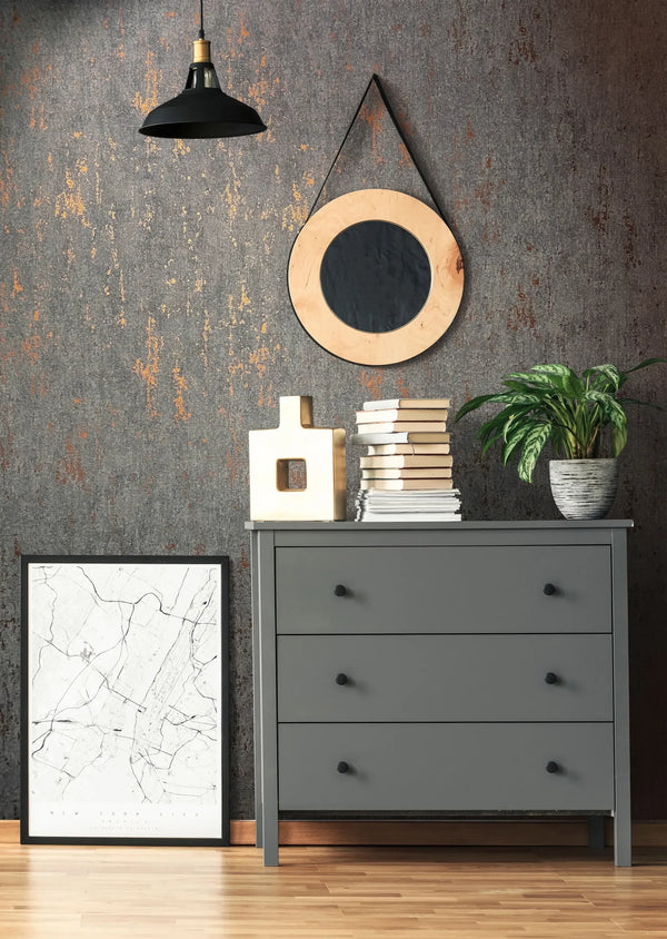 Marburg 35146 wallpaper lounge feature wall behind a grey dresser with black pendant light, round hanging mirror, stacked books, potted plant and a framed map, modern industrial vibe.