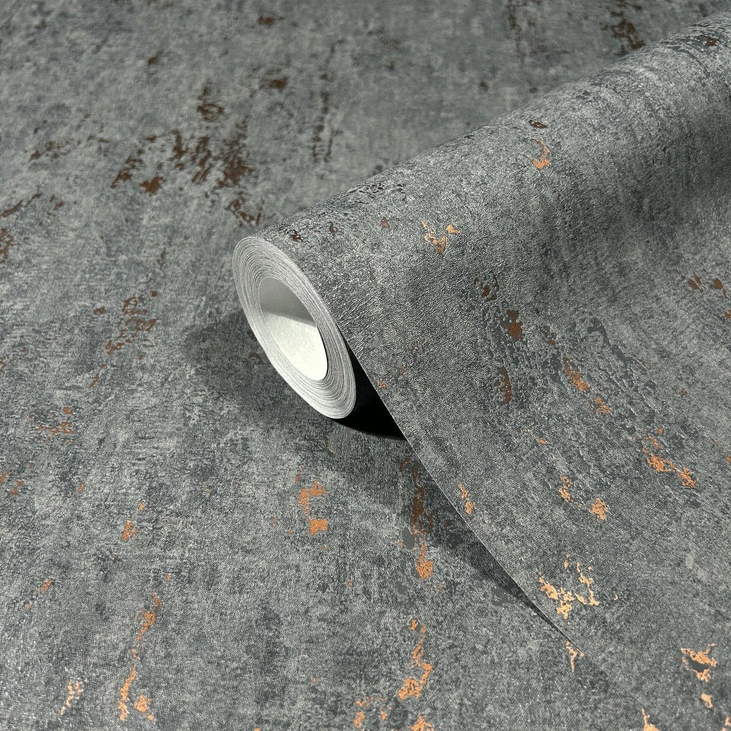 Marburg 35146 wallpaper close-up of gray textured finish with distressed copper flecks, roll partially unrolled.