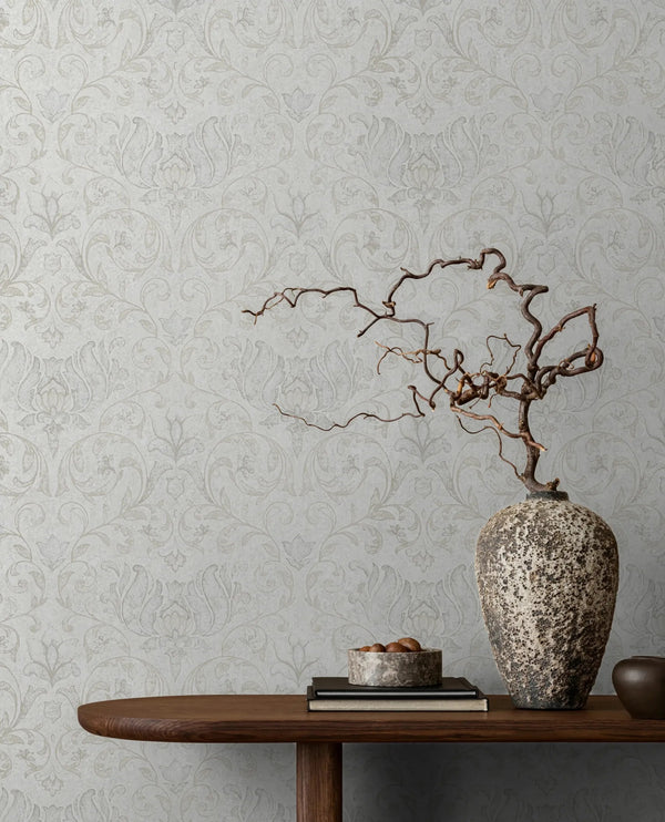 Marburg 35148 wallpaper lounge feature wall with wooden console table, speckled vase holding twisted branches, books and small bowl, serene minimalist mood.