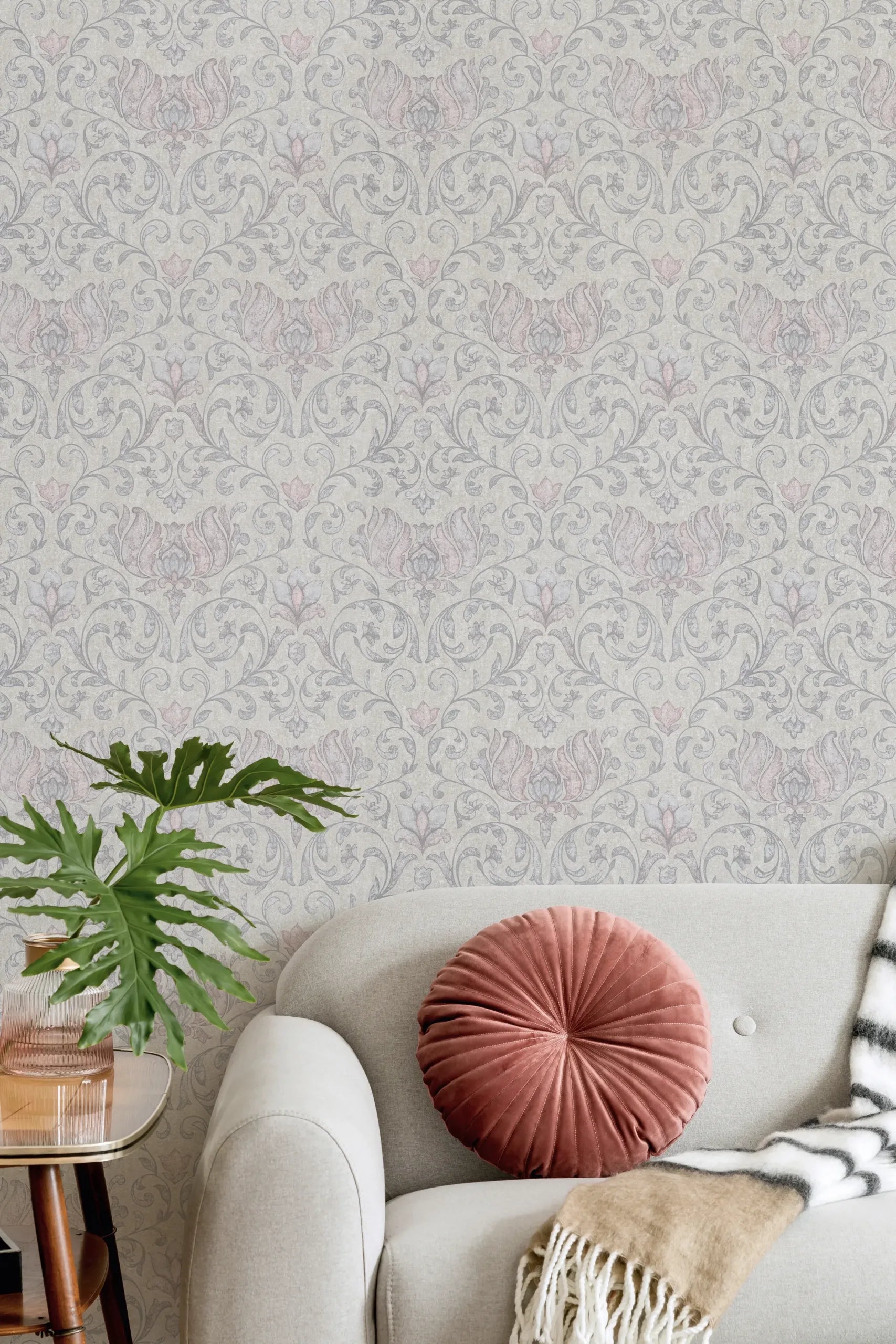 Marburg 35150 wallpaper on a lounge feature wall behind a light sofa with a round cushion, striped throw, side table and leafy plant for a calm, cozy feel.