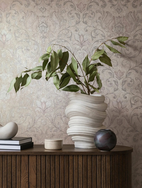 Marburg 35152 wallpaper in a lounge feature wall behind a slatted wood sideboard with a sculptural vase of leafy branches, stacked books and small ornaments for a calm, elegant mood.