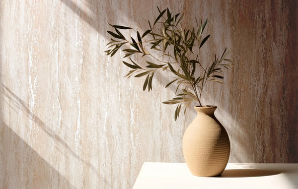 Marburg 35154 wallpaper lounge feature wall with textured neutral finish behind a table holding a ceramic vase with leafy branch, sunlit and serene.