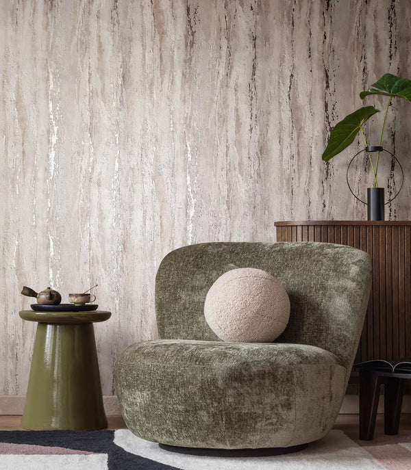 Marburg 35157 wallpaper lounge feature wall behind a plush chair with round cushion, ceramic side table with tea set, slatted cabinet with sculptural plant, serene contemporary mood.