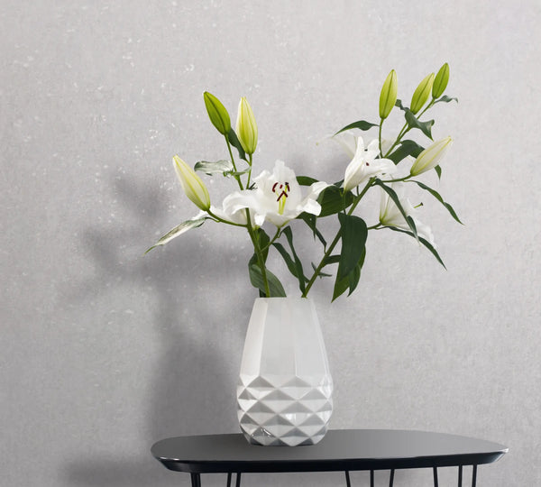 Marburg 35161 wallpaper in a lounge feature wall behind a black side table holding a white faceted vase of white lilies for a calm minimalist look.