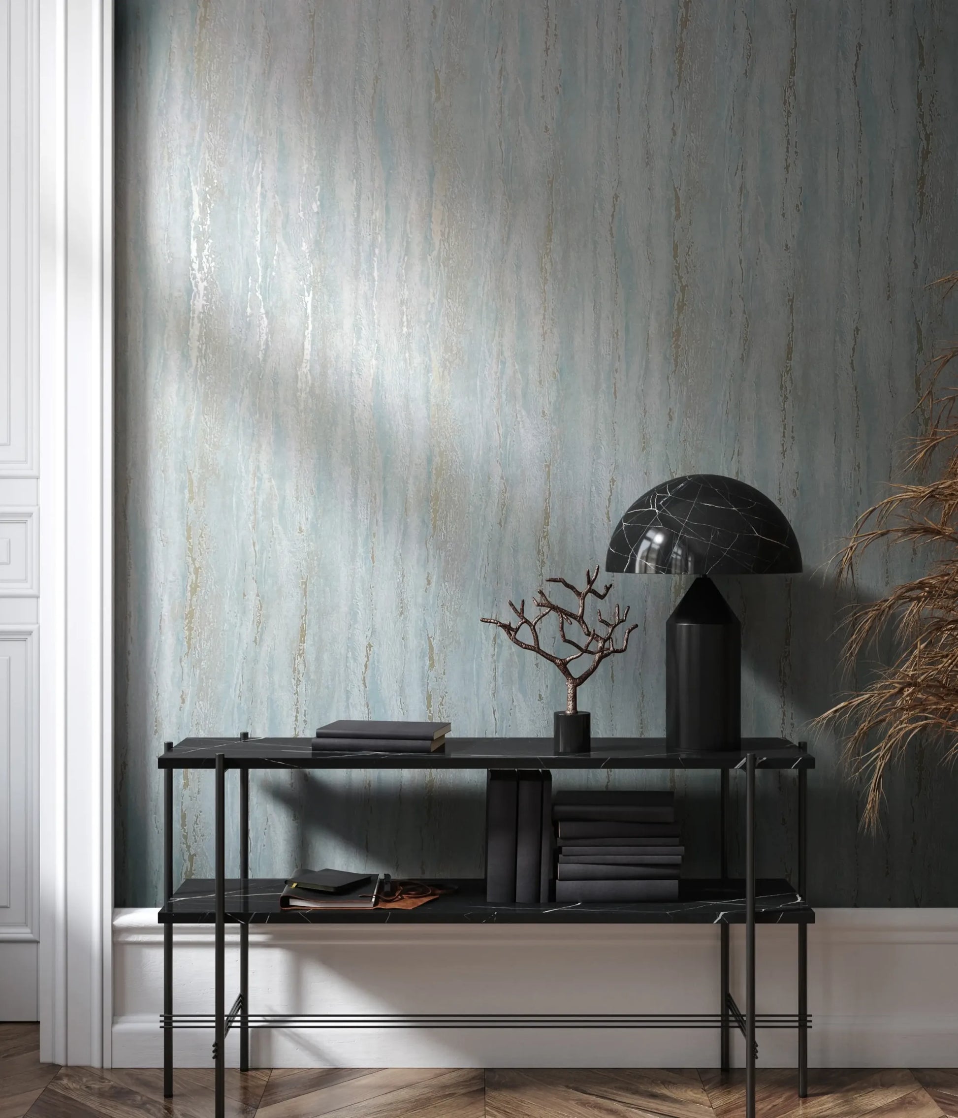 Marburg 35165 wallpaper lounge feature wall with black console table, marble dome lamp, stacked books, branch sculpture, dried grasses, and soft moody light.