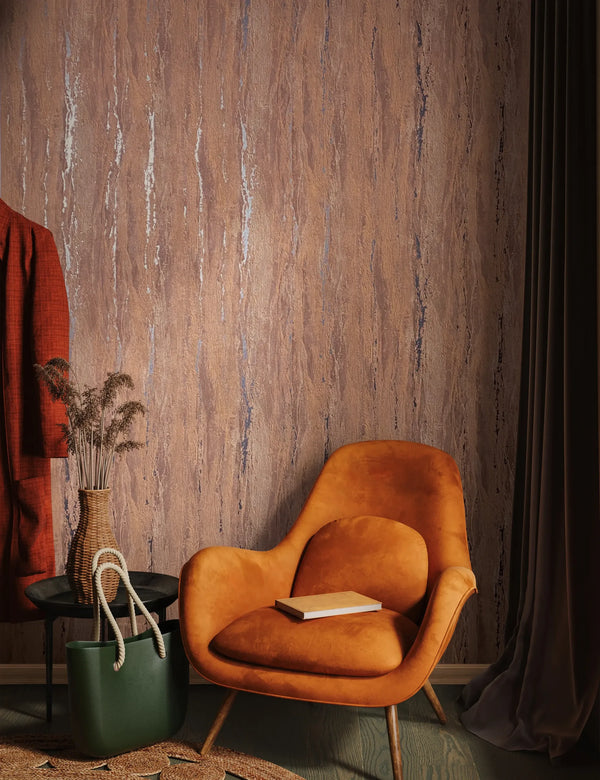 Marburg 35166 wallpaper lounge feature wall behind an orange armchair with a book, round black side table with woven vase and dried grasses, green tote and dark drapes, warm cozy mood.