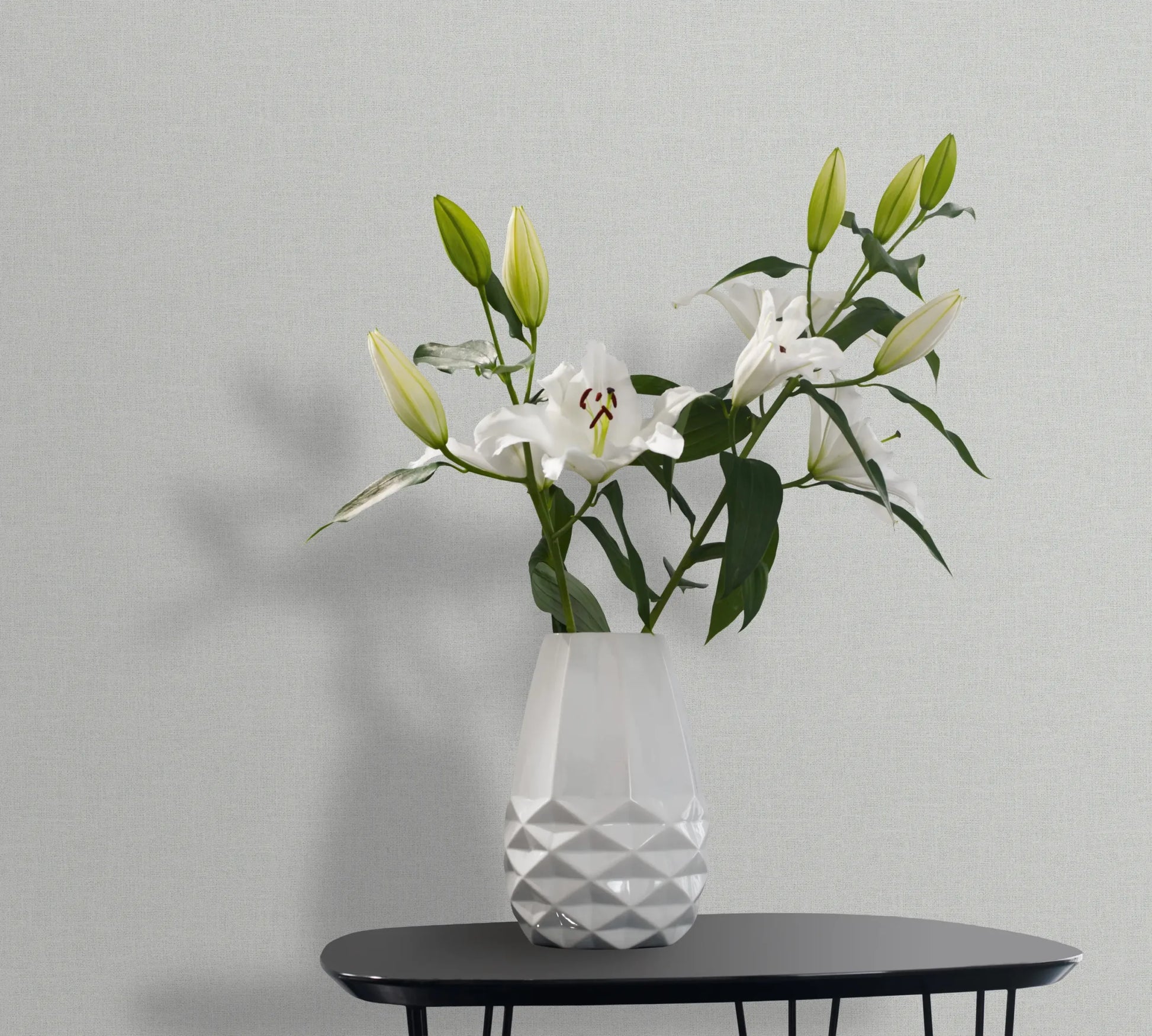 Marburg 47605 wallpaper lounge feature wall with a black side table and faceted white vase of lilies, calm and modern.