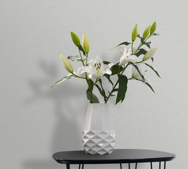 Marburg 47605 wallpaper lounge feature wall with a black side table and faceted white vase of lilies, calm and modern.