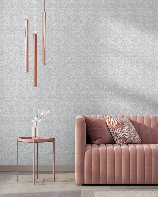 Marburg 47608 wallpaper lounge feature wall behind a pink channel‑tufted sofa, slim metallic pendant lights, and a round side table with a vase for a calm contemporary mood.