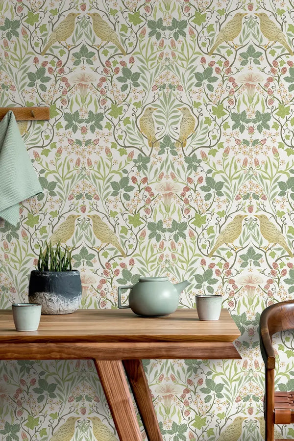 Marburg 47620 wallpaper lounge feature wall with botanical bird motif behind a wooden table, ceramic teapot and cups, small potted plant, and a peg rail with hanging towel for a relaxed feel.