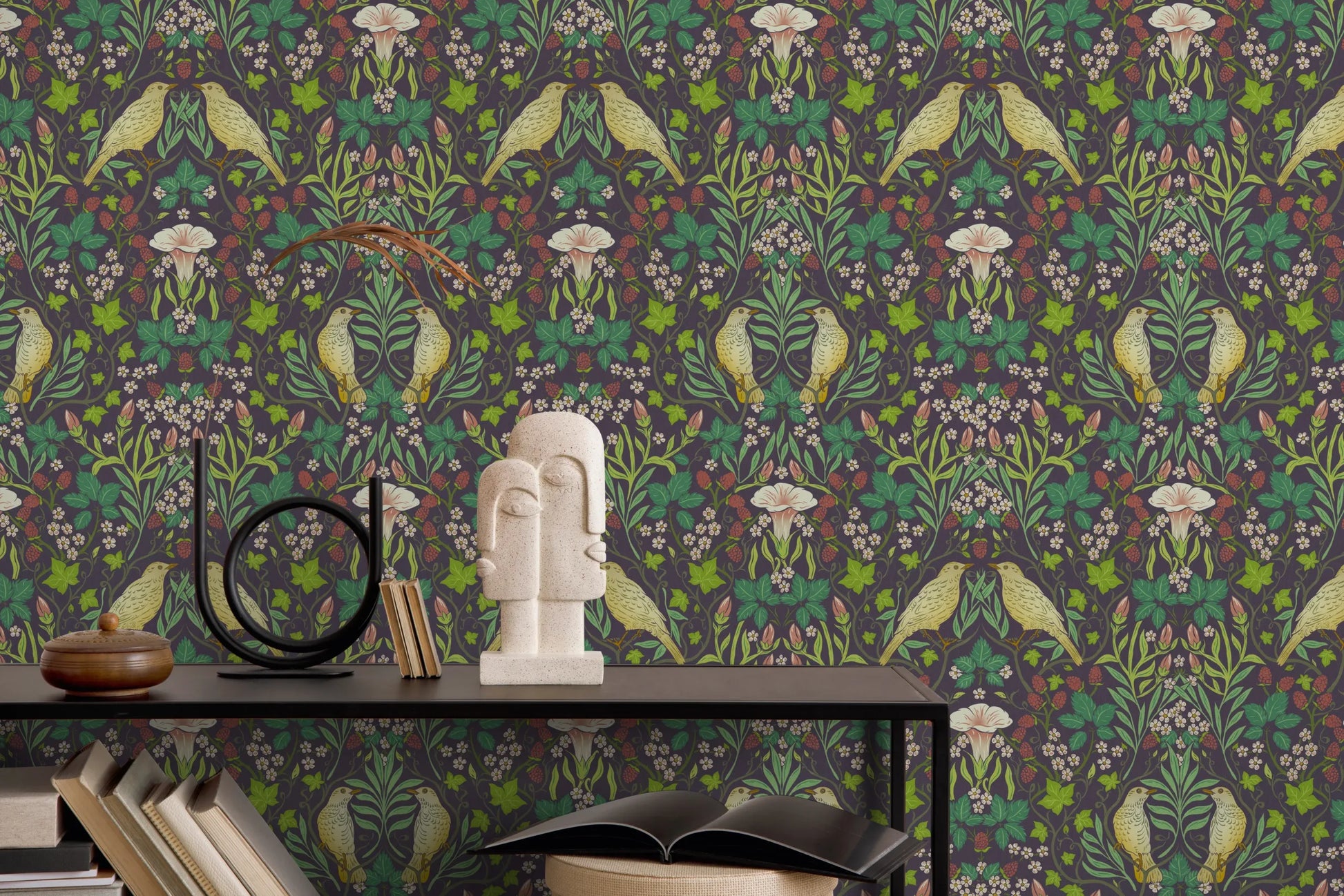 Marburg 47621 wallpaper lounge feature wall with botanical bird pattern behind a slim console table styled with books, a sculptural bust, a black ring ornament and a lidded pot for an artful, cozy mood.