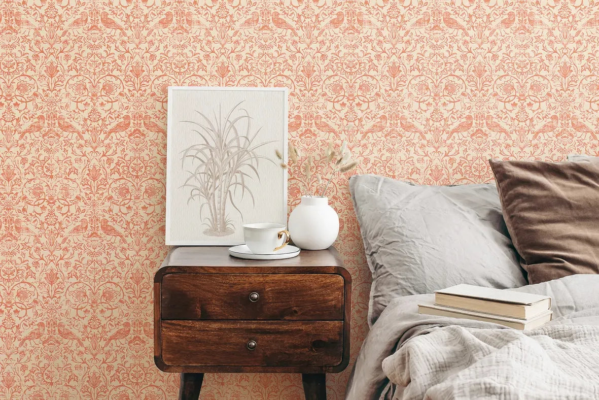 Marburg 47622 wallpaper bedroom feature wall behind wooden bedside table with framed botanical art, white vase and teacup, next to rumpled bed with pillows and books for a cozy mood.