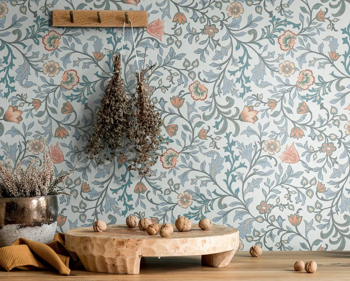 Marburg 47627 wallpaper lounge feature wall with floral pattern, wooden peg rail with dried bouquets above a rustic console displaying a low wooden serving board, metal planter and scattered walnuts, calm natural mood.