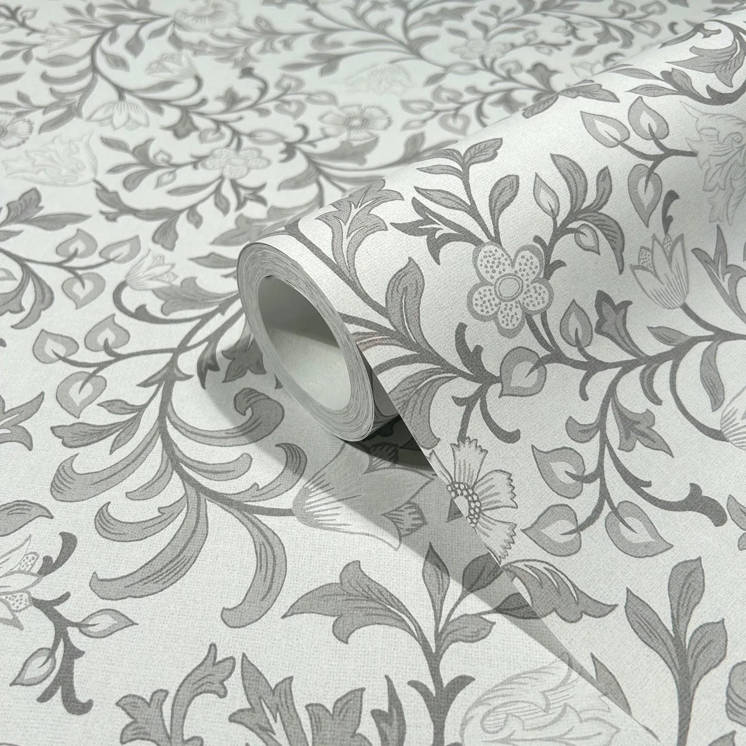 Marburg 47628 wallpaper close-up of gray floral vine pattern on light textured background, roll partially unrolled.