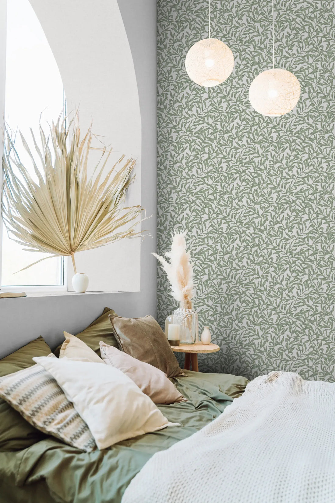 Marburg 47640 wallpaper in a calm bedroom feature wall behind a low bed with layered pillows, small round side table with vase and candle, dried botanicals, and two globe pendant lights.