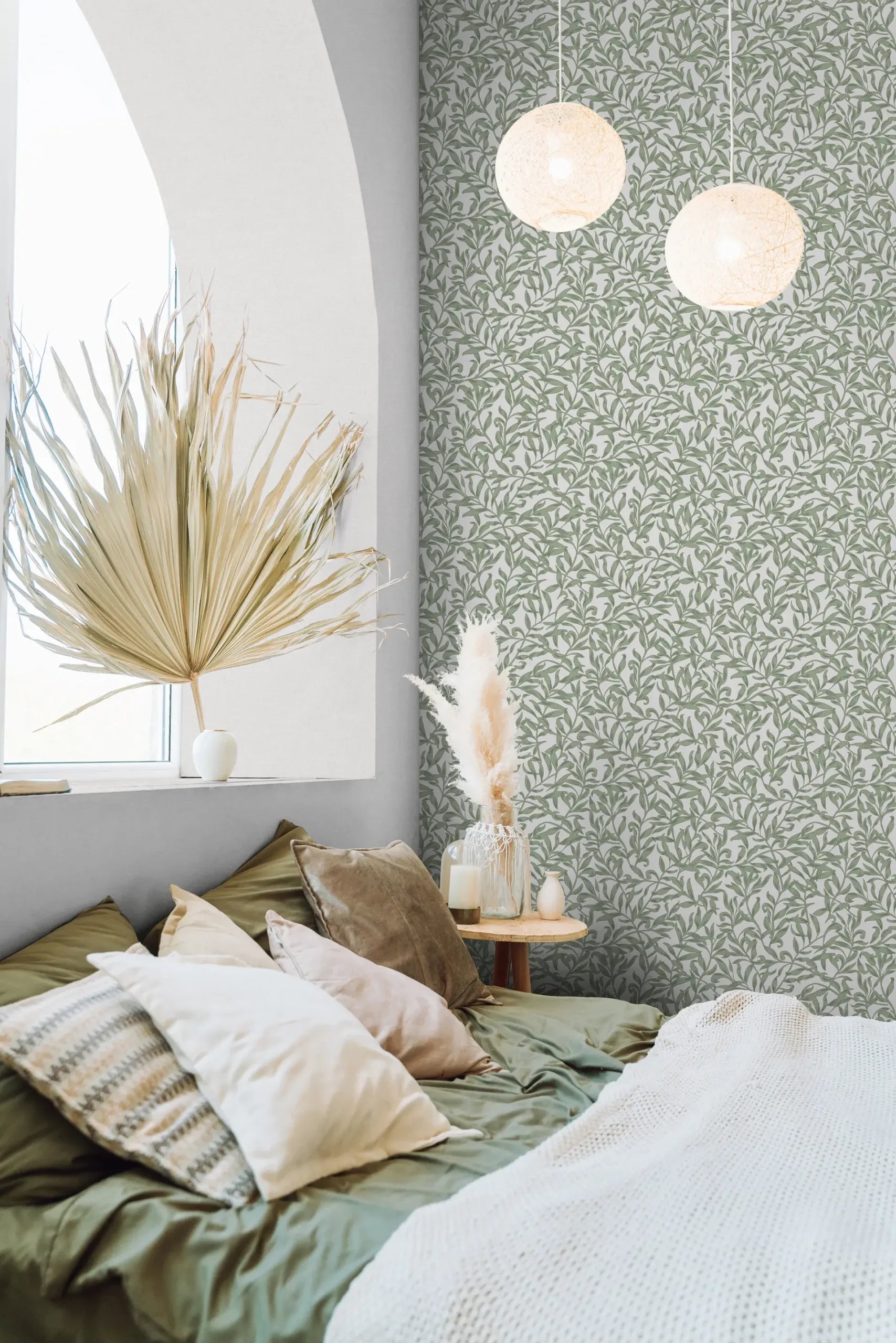 Marburg 47640 wallpaper in a calm bedroom feature wall behind a low bed with layered pillows, small round side table with vase and candle, dried botanicals, and two globe pendant lights.
