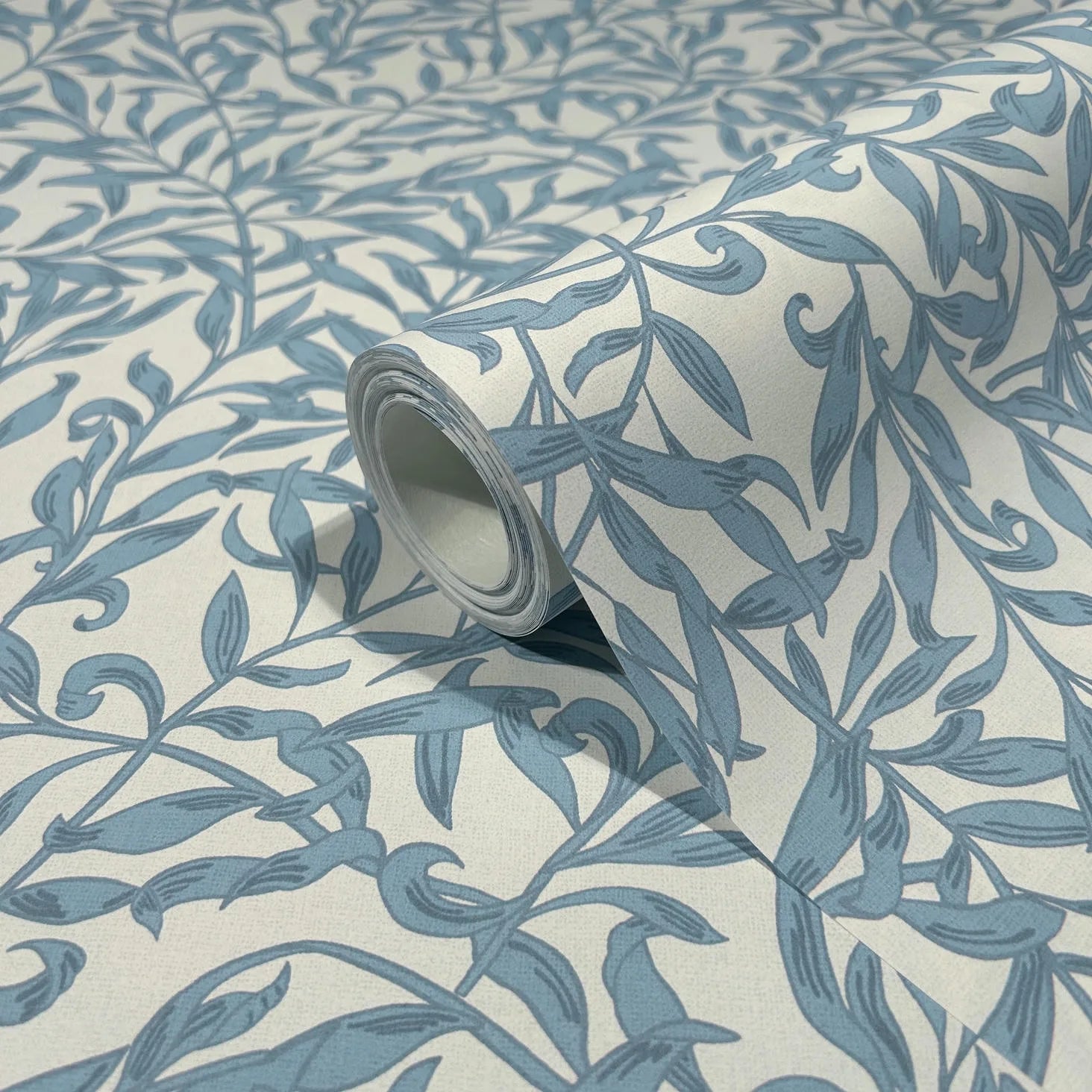Marburg 47642 wallpaper close-up roll showing blue leafy vine motif on a light background.