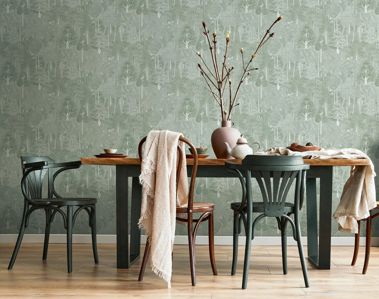 Marburg 47651 wallpaper dining room feature wall behind a wood table with mixed chairs, branch vase, teapot and draped linens, calm rustic mood.