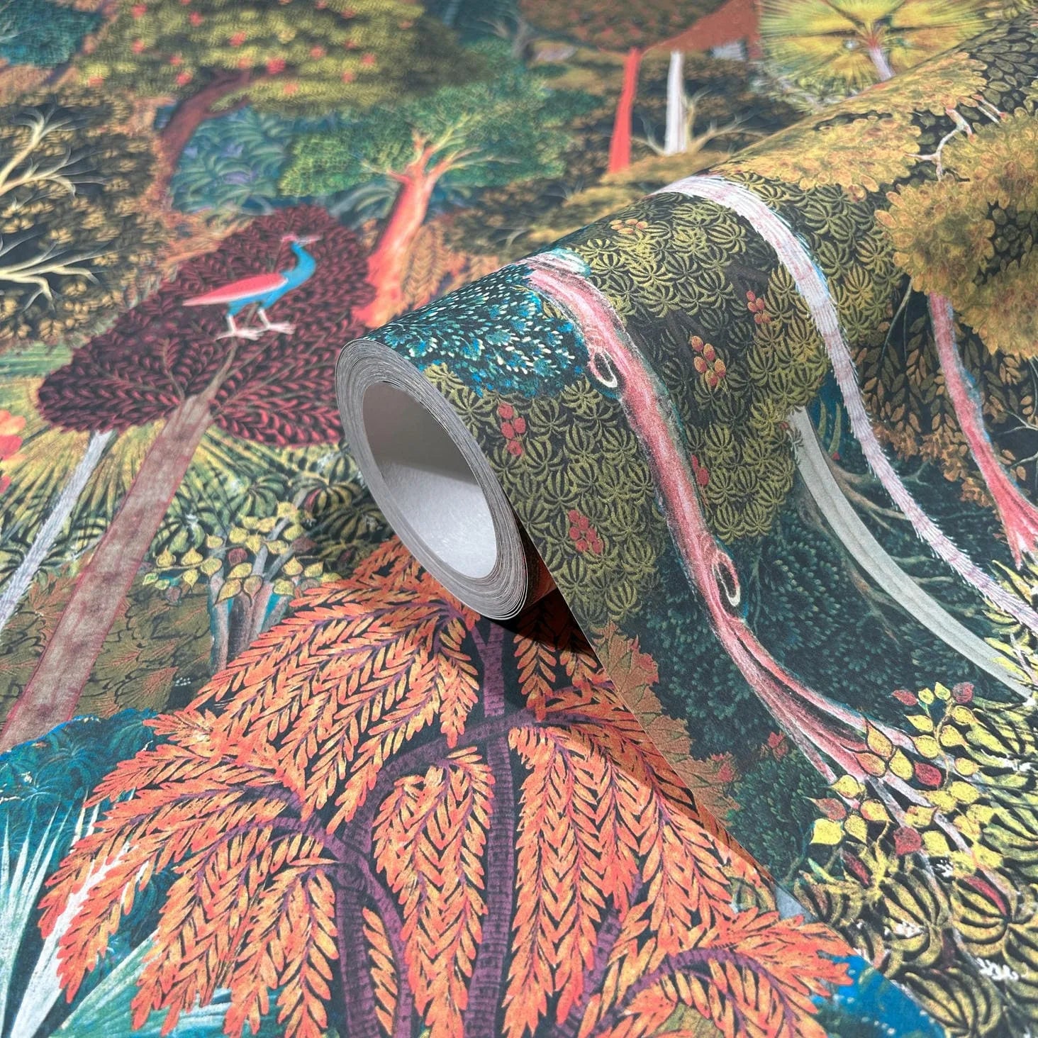 Marburg 47652 wallpaper roll close-up showing dense woodland illustration with trees, foliage, and a peacock.