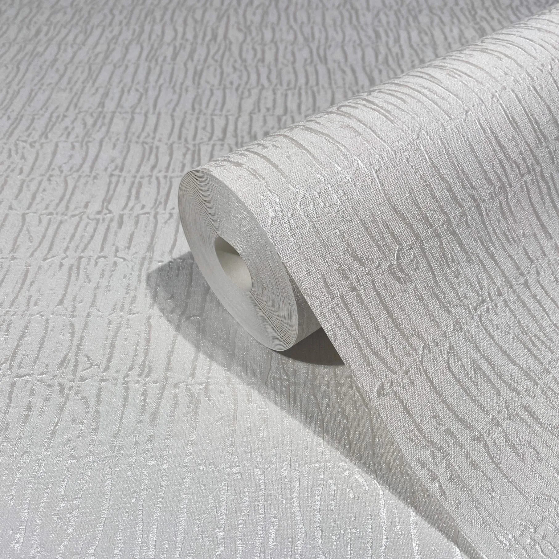 Marburg Kumano 34501 A white wallpaper roll with raised vertical striations resting on the same unrolled paper, showing the tone-on-tone texture and subtle sheen.